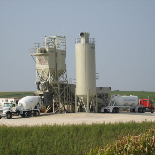 A large cement mixer truck parked next to a large truck.